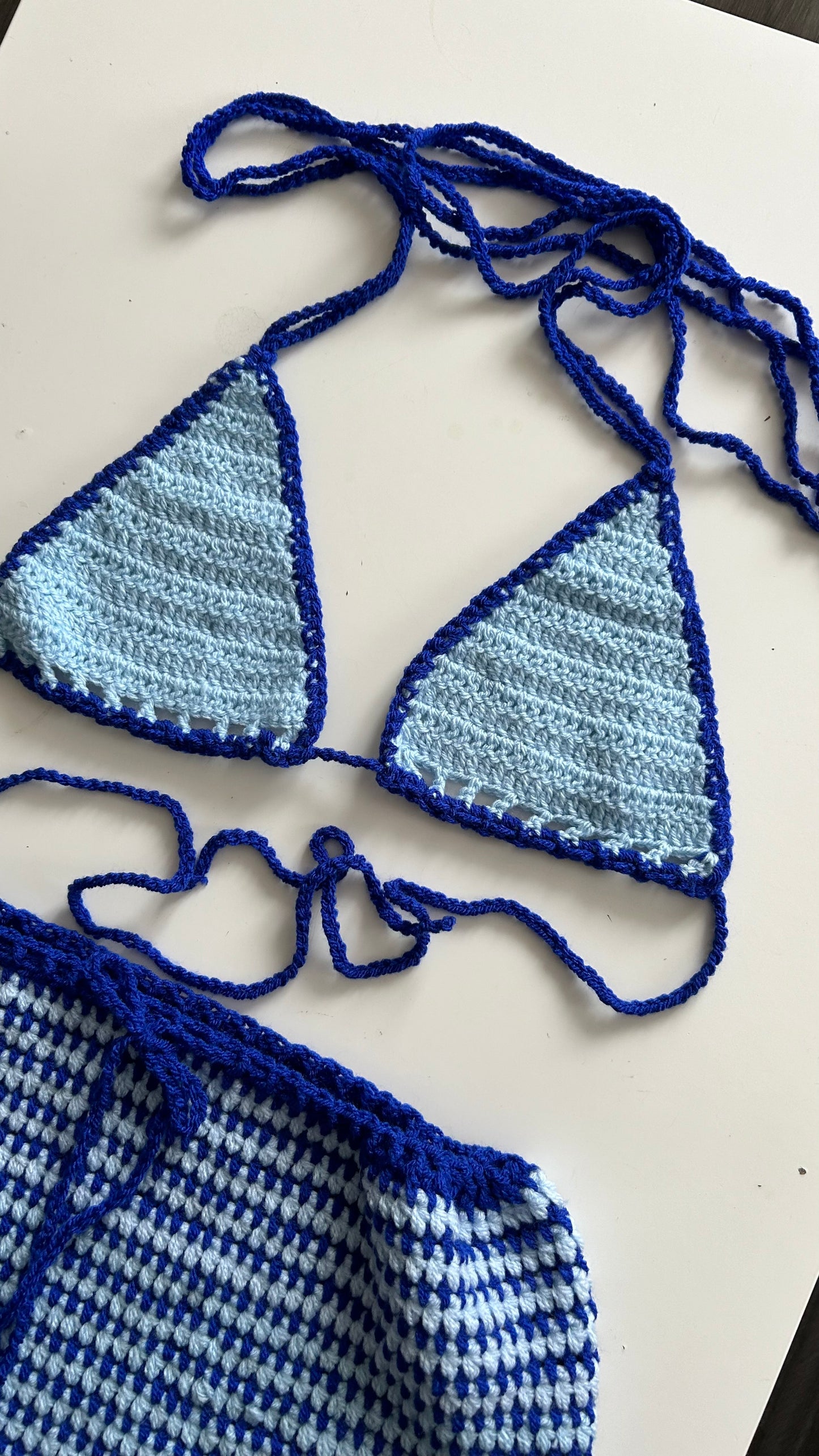A two-piece handmade outfit consisting of a blue bikini top and shorts, laid out on a flat surface.