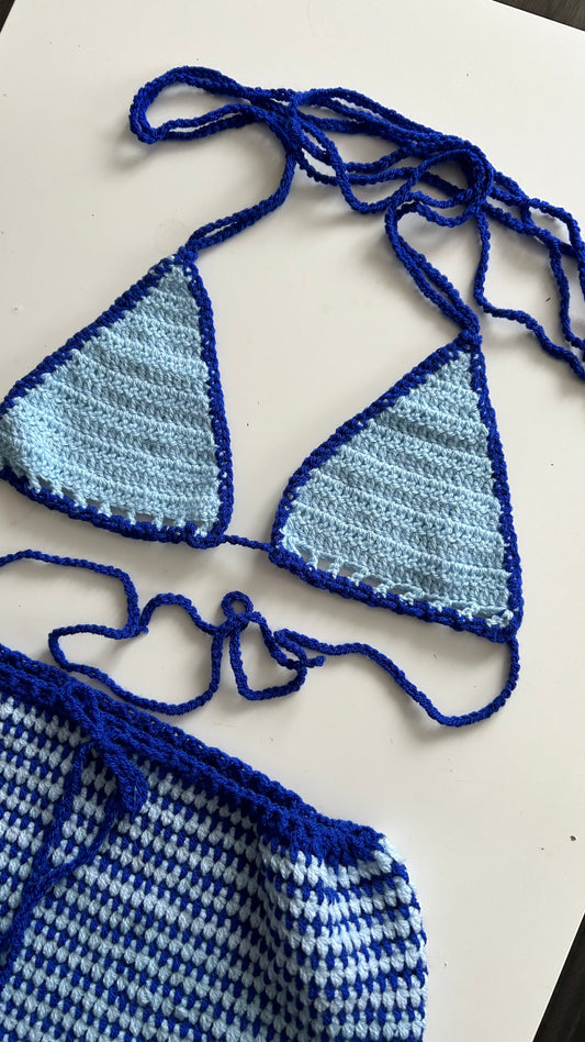 A two-piece handmade outfit consisting of a blue bikini top and shorts, laid out on a flat surface.
